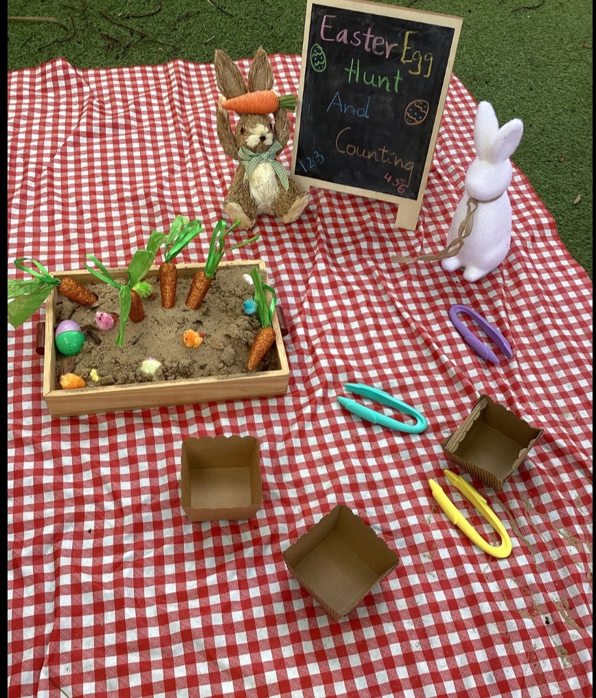 Easter egg hunt and counting tray set up on a picnic rug