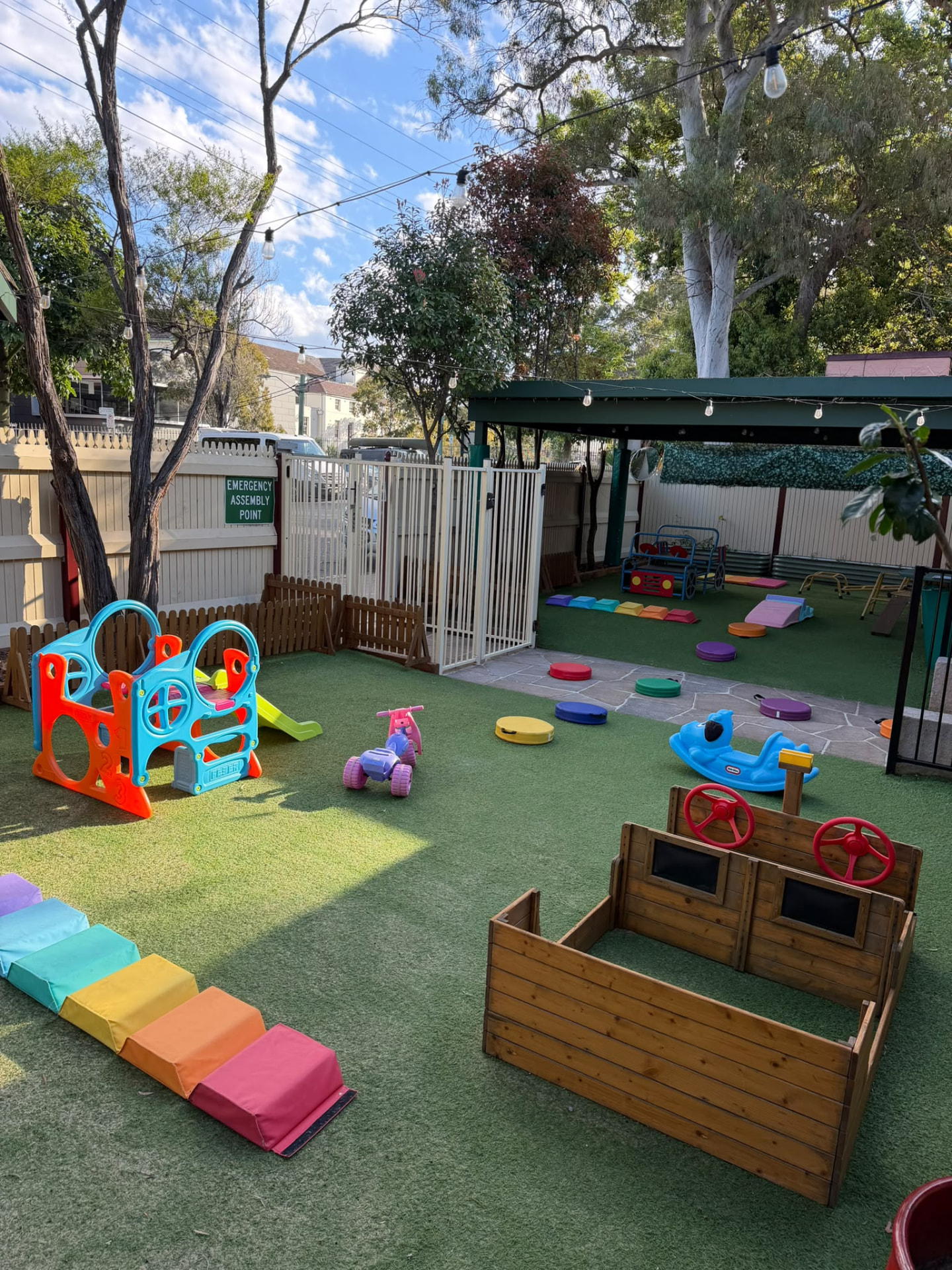 Fenced outdoor yard at Little Woods where children climb, balance and run